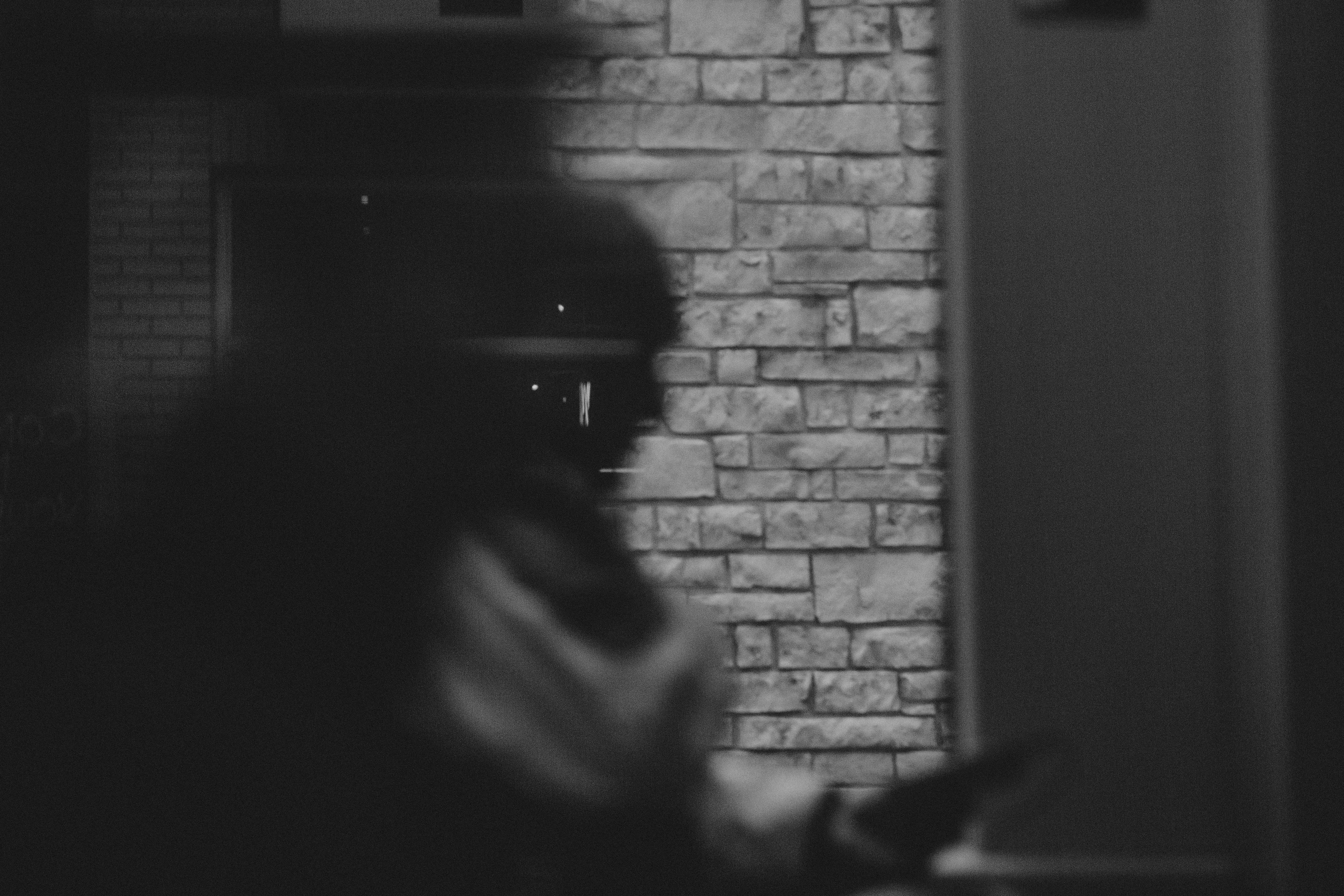 grayscale photography of person's profile standing beside gray wall